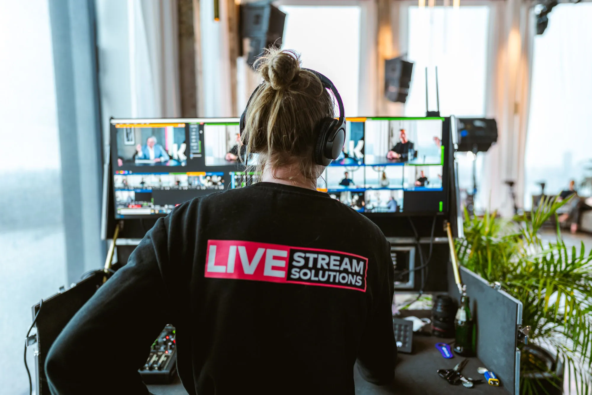 Crewlid van Livestream Solutions met koptelefoon bedient de beeldregie achter multiview-monitoren tijdens een live uitzending.
