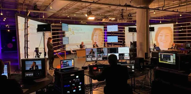 Studio met regiemonitoren, camera's en een decor waar een gesprek wordt opgenomen.