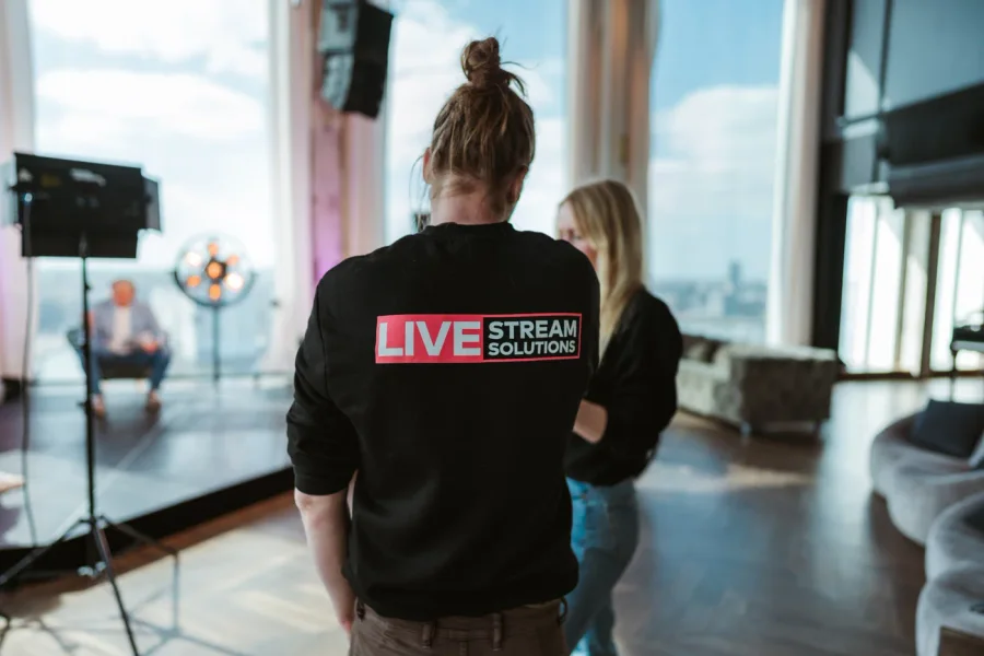 Crewlid van Livestream Solutions bij een camera op statief in een lichte ruimte op locatie.