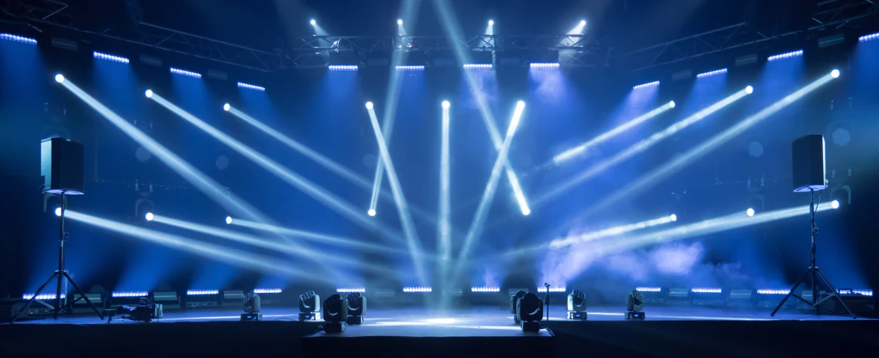 Leeg podium met blauwe lichtbundels en een groot scherm, klaar voor de start van een live event.