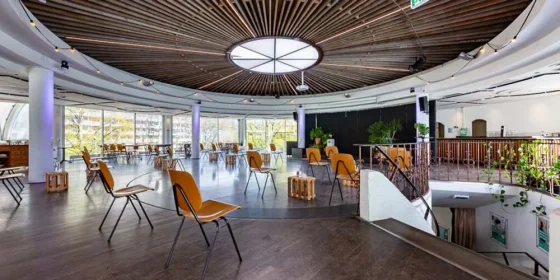 Ronde ruimte met een lichtkoepel, stoelen en een LED-scherm.