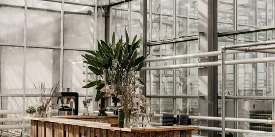 Industriële ruimte met stalen ramen, een bar en een groot bloemstuk.