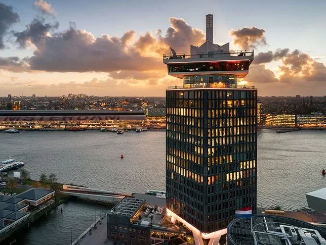 De A'DAM Tower aan het IJ in Amsterdam vanuit de lucht, bij zonsondergang.