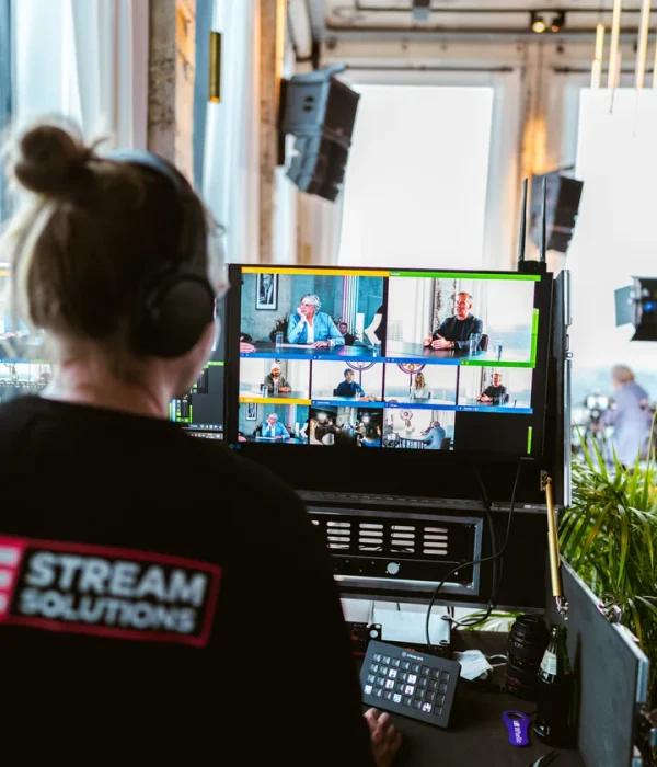 Crewlid van Livestream Solutions achter de regie, met de multiviewmonitoren van de uitzending in beeld.