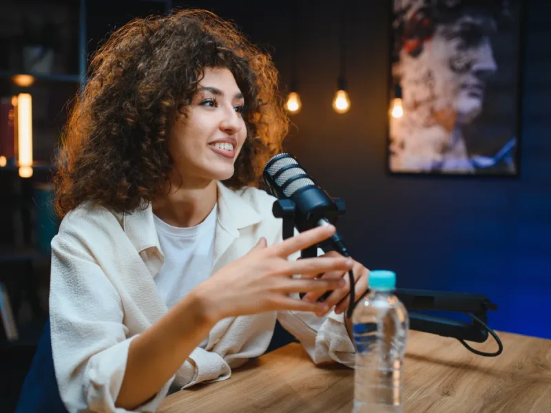 Spreker vertelt haar verhaal voor de microfoon in een warm uitgelichte studio.