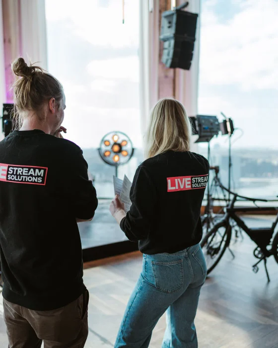 Twee crewleden van Livestream Solutions bouwen de belichting op bij een raam met uitzicht over de stad.
