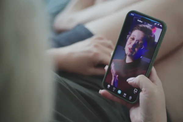 Kijker bekijkt een korte verticale video van een spreker op een telefoon, geknipt uit het webinar.