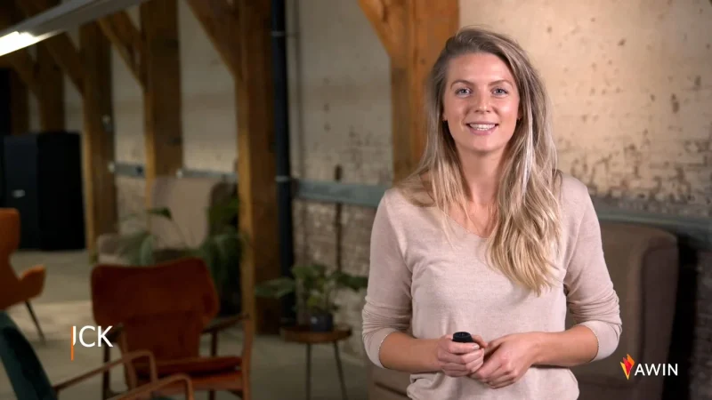 Presentatrice vertelt haar verhaal in een industriële ruimte met houten balken, met het logo van Awin in beeld.